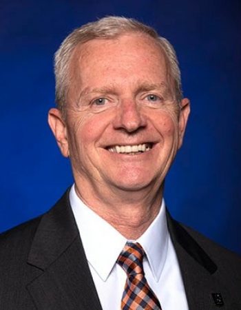 Jason Kelley, Chairman of the Board, smiling in front of a blue background.